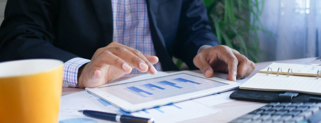 A man looks at bar graphs on his tablet
